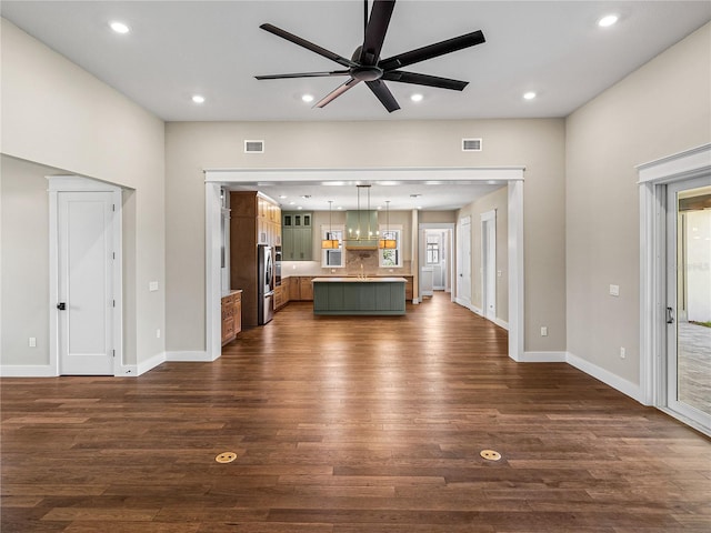 unfurnished living room featuring hardwood / wood-style flooring, sink, and ceiling fan