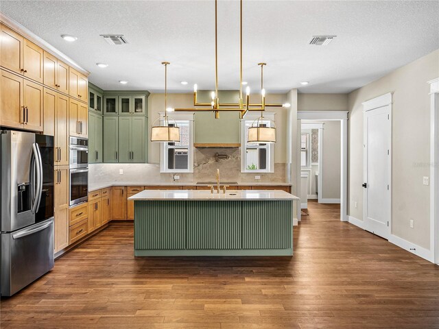 kitchen featuring a kitchen island with sink, decorative backsplash, hardwood / wood-style flooring, and stainless steel appliances