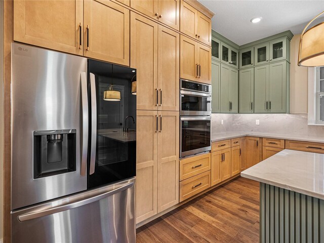 kitchen with tasteful backsplash, light brown cabinets, light stone countertops, appliances with stainless steel finishes, and dark wood-type flooring