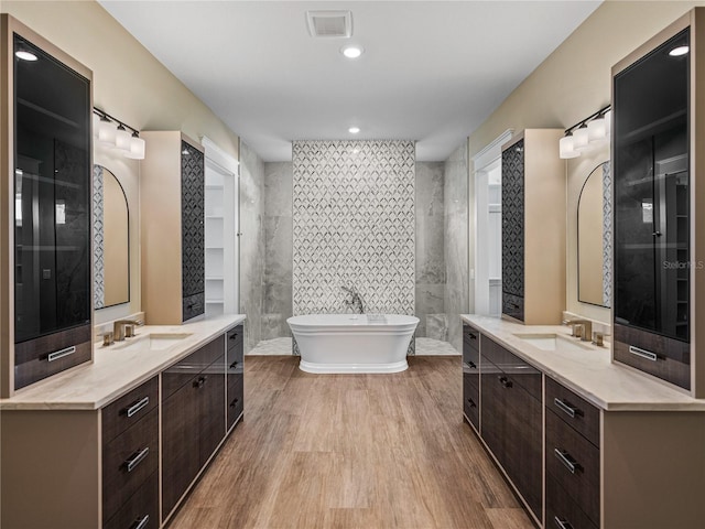 bathroom featuring double sink vanity, a bath, and tile walls