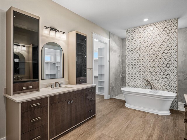 bathroom featuring a bath, vanity, and tile walls