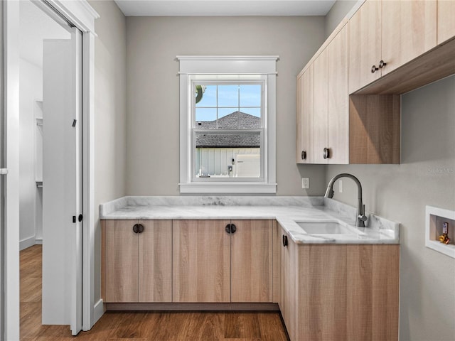 kitchen with sink, light stone counters, and hardwood / wood-style floors