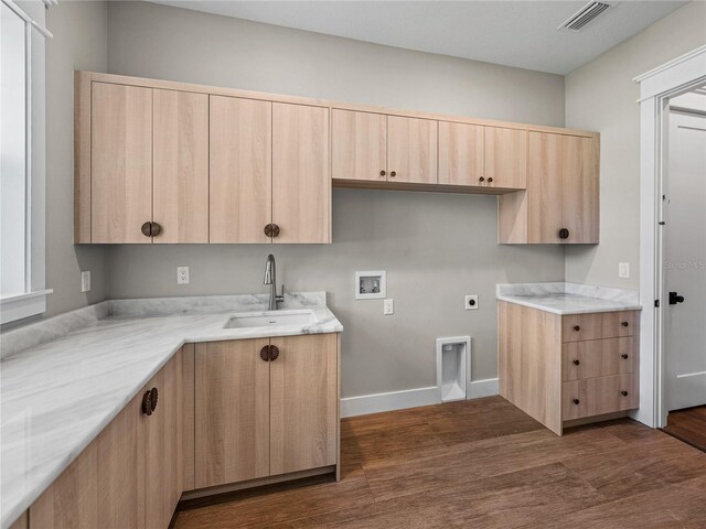 kitchen with dark wood-type flooring, light stone countertops, light brown cabinets, and sink