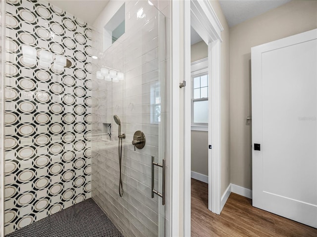 bathroom with a tile shower and wood-type flooring