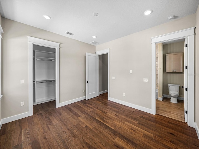 unfurnished bedroom with dark hardwood / wood-style floors, a closet, and ensuite bathroom