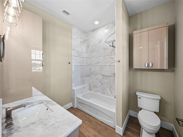 full bathroom with vanity, tiled shower / bath combo, wood-type flooring, and toilet