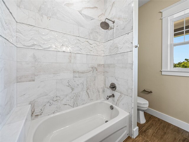 bathroom with hardwood / wood-style flooring, tiled shower / bath combo, and toilet