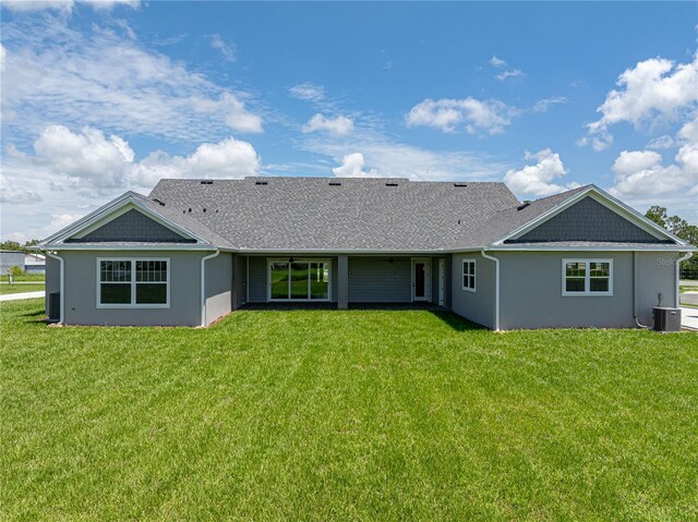 back of property featuring central AC and a lawn