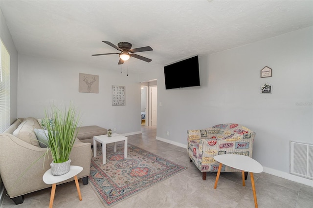 living area with baseboards, a textured ceiling, visible vents, and a ceiling fan