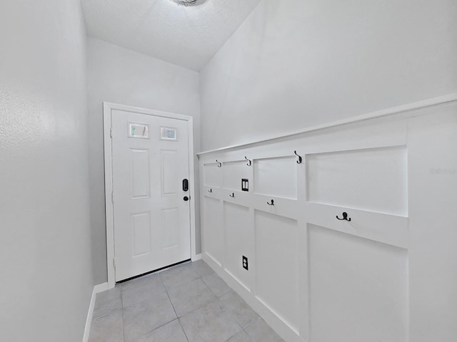 doorway with light tile patterned floors and a textured ceiling