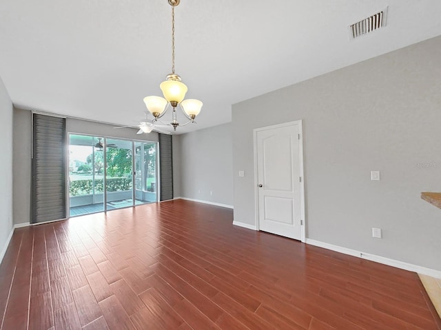 unfurnished room with a notable chandelier and dark hardwood / wood-style flooring