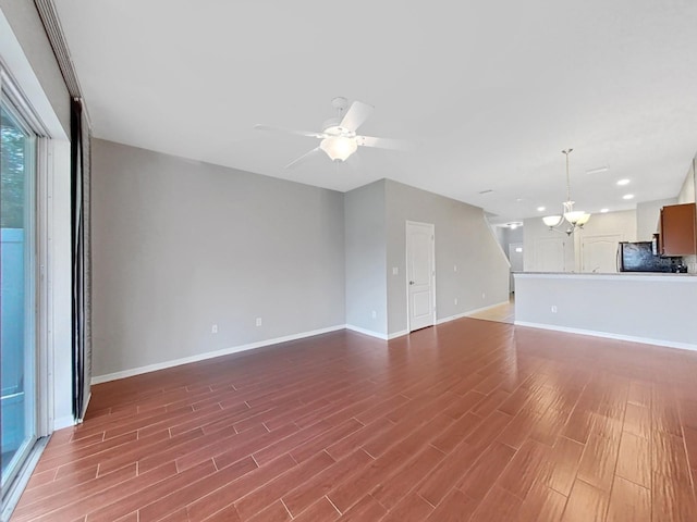 unfurnished living room featuring hardwood / wood-style flooring and ceiling fan with notable chandelier