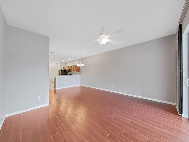 unfurnished living room with ceiling fan with notable chandelier and light wood-type flooring