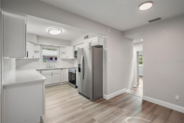 kitchen featuring decorative backsplash, stainless steel appliances, light hardwood / wood-style floors, and white cabinets