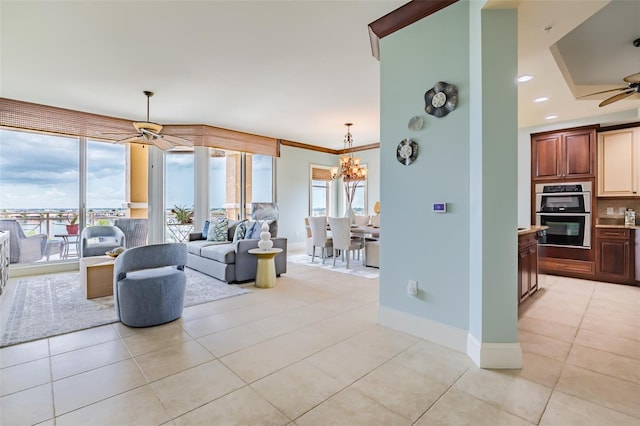 living area with light tile patterned floors, recessed lighting, ceiling fan with notable chandelier, baseboards, and ornamental molding