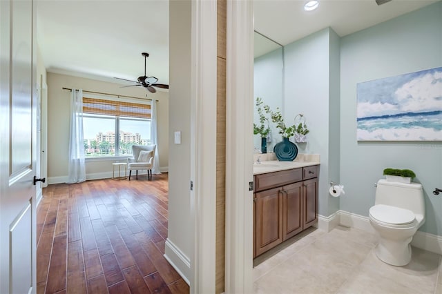 bathroom featuring baseboards, toilet, ceiling fan, wood finished floors, and vanity