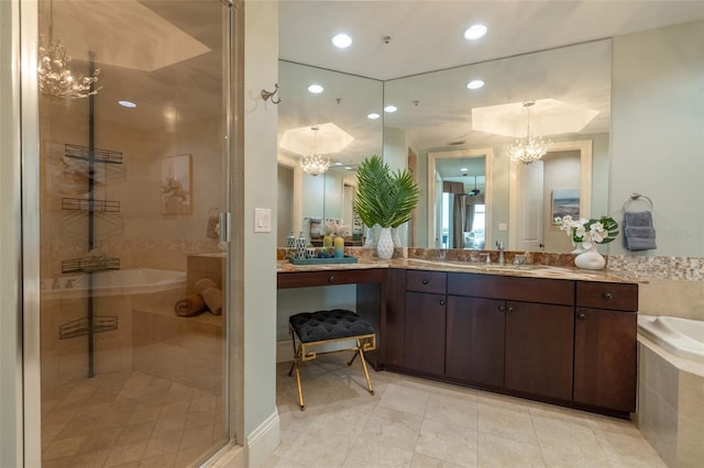bathroom featuring an inviting chandelier, vanity, a bath, and a stall shower