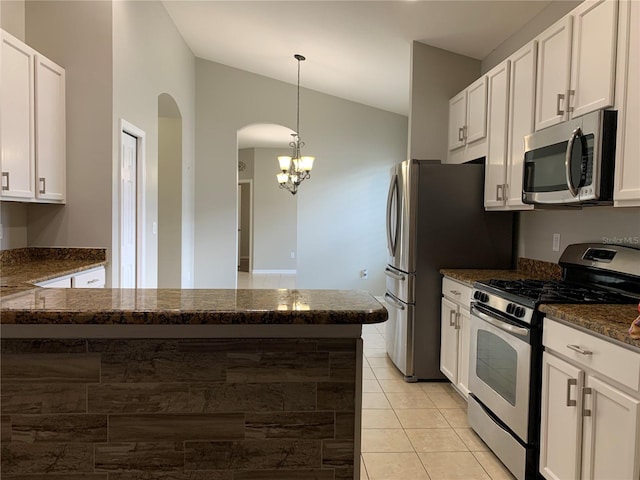 kitchen featuring lofted ceiling, stainless steel appliances, dark stone counters, and white cabinets