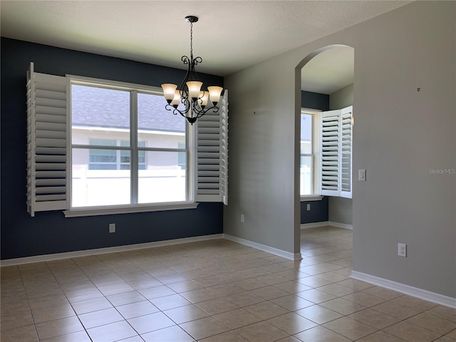 tiled spare room with a chandelier and a textured ceiling