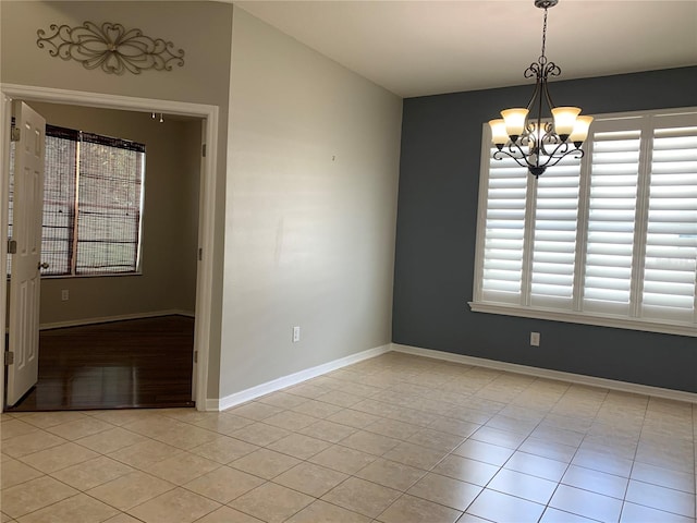 unfurnished room featuring a healthy amount of sunlight, a notable chandelier, and light tile patterned floors