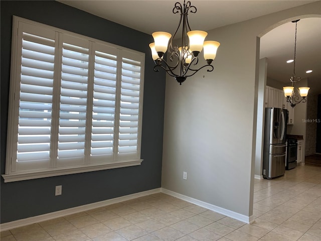 spare room featuring a wealth of natural light, an inviting chandelier, and light tile patterned flooring