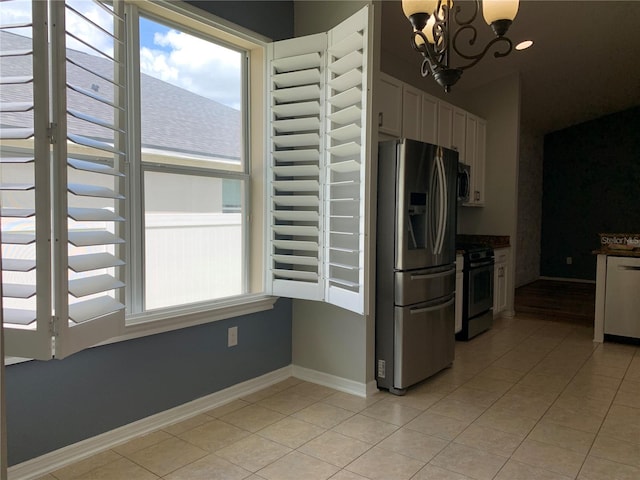 kitchen featuring white cabinets, appliances with stainless steel finishes, light tile patterned floors, and a notable chandelier