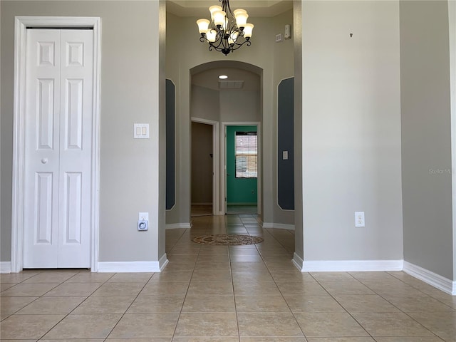 tiled foyer entrance with an inviting chandelier