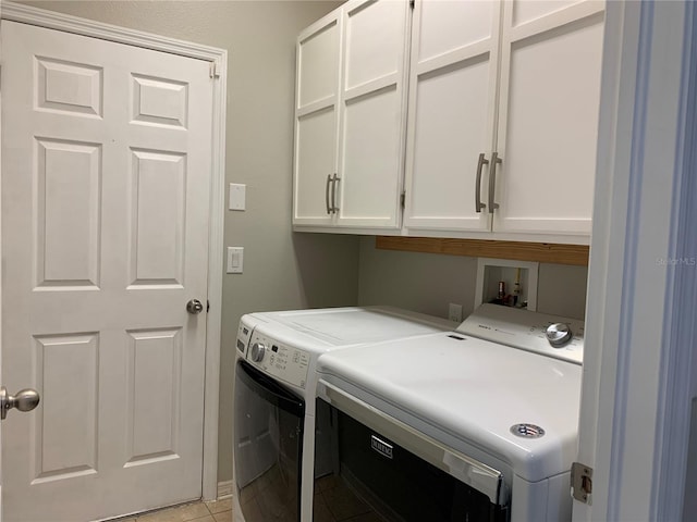 clothes washing area with washing machine and clothes dryer, cabinets, and light tile patterned flooring