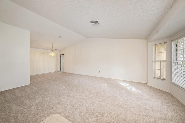 carpeted spare room featuring a textured ceiling, vaulted ceiling, and a notable chandelier