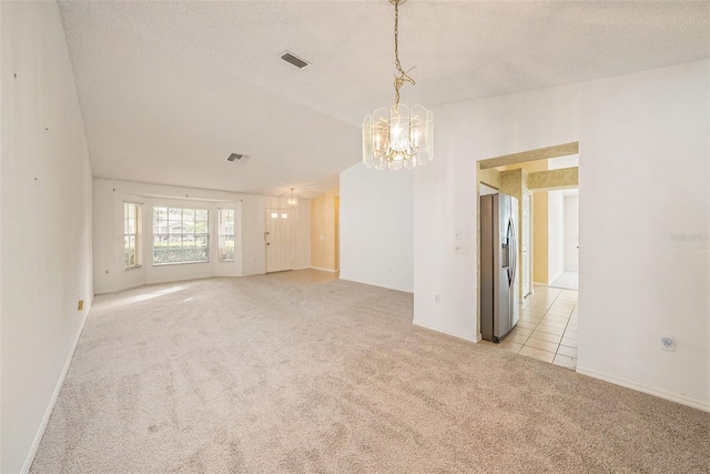 carpeted spare room featuring a notable chandelier and a textured ceiling