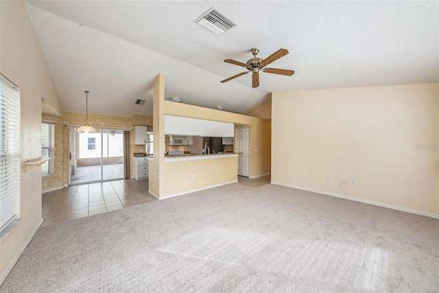 unfurnished living room featuring ceiling fan, light colored carpet, lofted ceiling, and a textured ceiling