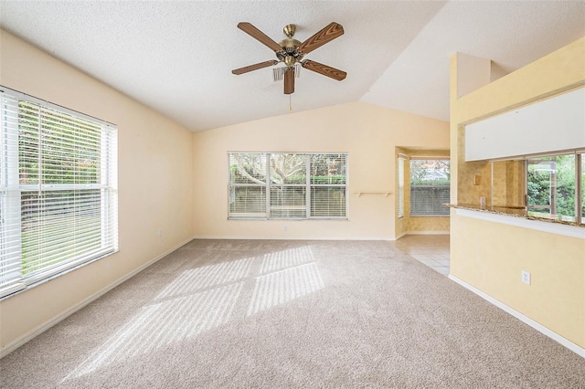 carpeted spare room featuring a textured ceiling, ceiling fan, plenty of natural light, and vaulted ceiling