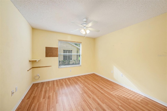 empty room featuring ceiling fan, light wood-type flooring, and a textured ceiling