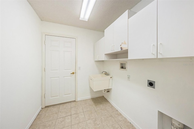 clothes washing area featuring cabinets, hookup for an electric dryer, washer hookup, a textured ceiling, and light tile patterned floors