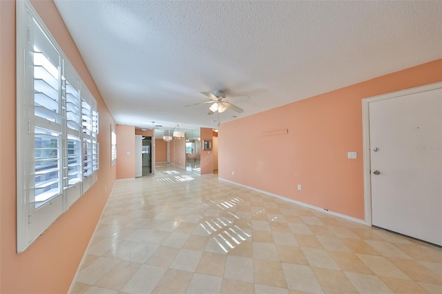 unfurnished living room featuring a textured ceiling, ceiling fan, and light tile patterned floors