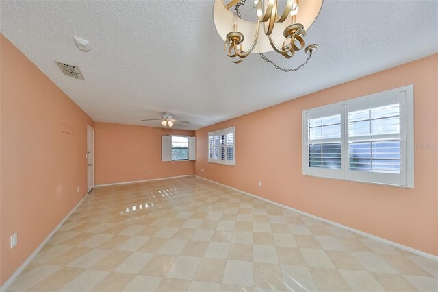 tiled spare room featuring ceiling fan with notable chandelier and a textured ceiling