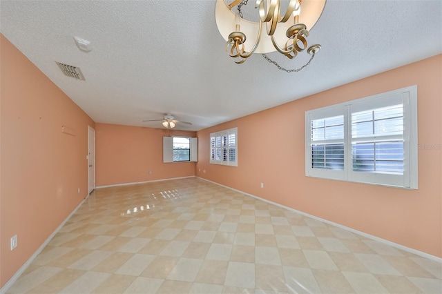 spare room featuring ceiling fan with notable chandelier and a textured ceiling