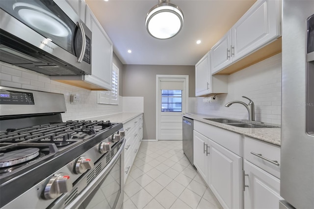 kitchen with light tile patterned floors, white cabinets, backsplash, stainless steel appliances, and sink