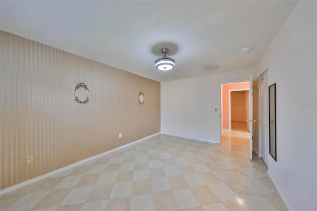 tiled empty room featuring a textured ceiling