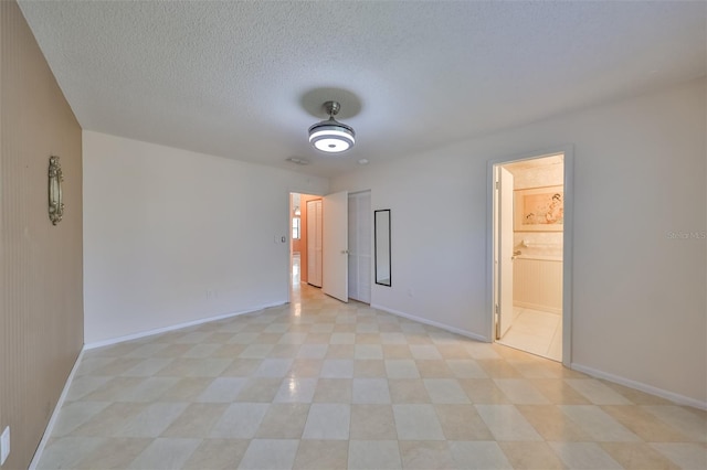 empty room featuring light tile patterned flooring and a textured ceiling