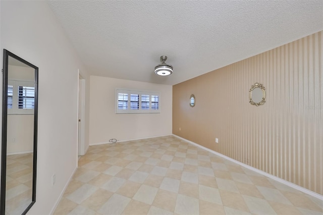 tiled empty room with a textured ceiling