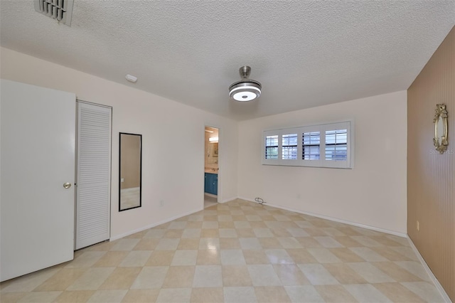 spare room featuring light tile patterned flooring and a textured ceiling