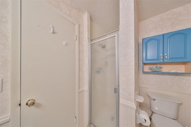 bathroom featuring a shower with door, toilet, and a textured ceiling