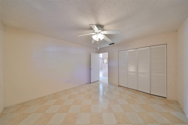 unfurnished bedroom featuring a textured ceiling, a closet, light tile patterned floors, and ceiling fan