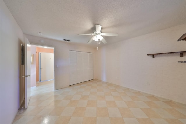 spare room with a textured ceiling, light tile patterned floors, and ceiling fan