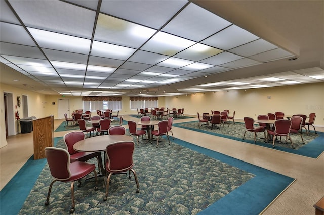 carpeted dining room with a drop ceiling