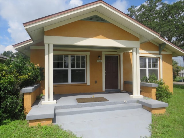 entrance to property with a porch and stucco siding