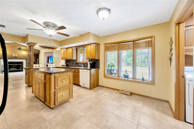 kitchen with washer / dryer, sink, dishwasher, a kitchen island, and ceiling fan