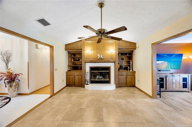 living room featuring ceiling fan, built in shelves, vaulted ceiling, and a textured ceiling