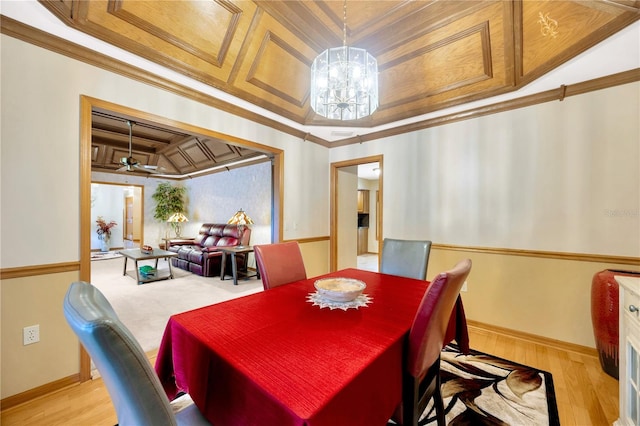 dining area featuring crown molding, ceiling fan with notable chandelier, light wood-type flooring, and a tray ceiling